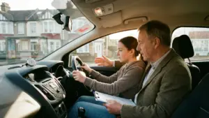 Intensive driving course mid-lesson — UK instructor and learner inside a car with clipboard and stopwatch