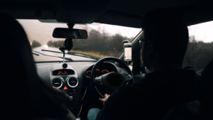 Right-hand-drive car interior on a wet UK road, suitable for a 40-hour intensive driving course for beginners.